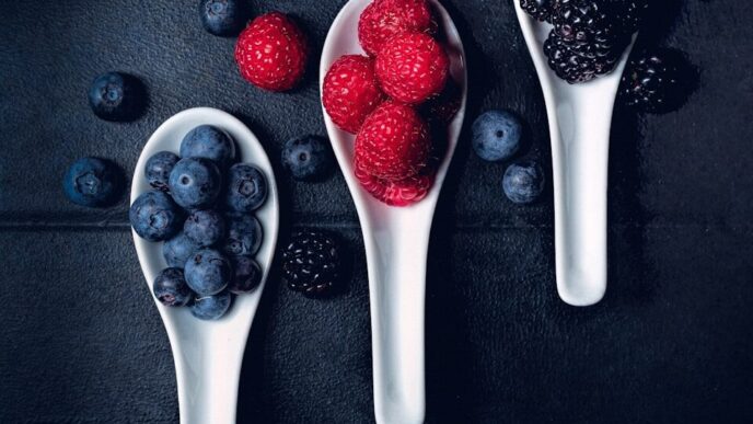 three ladles of berries on gray surface