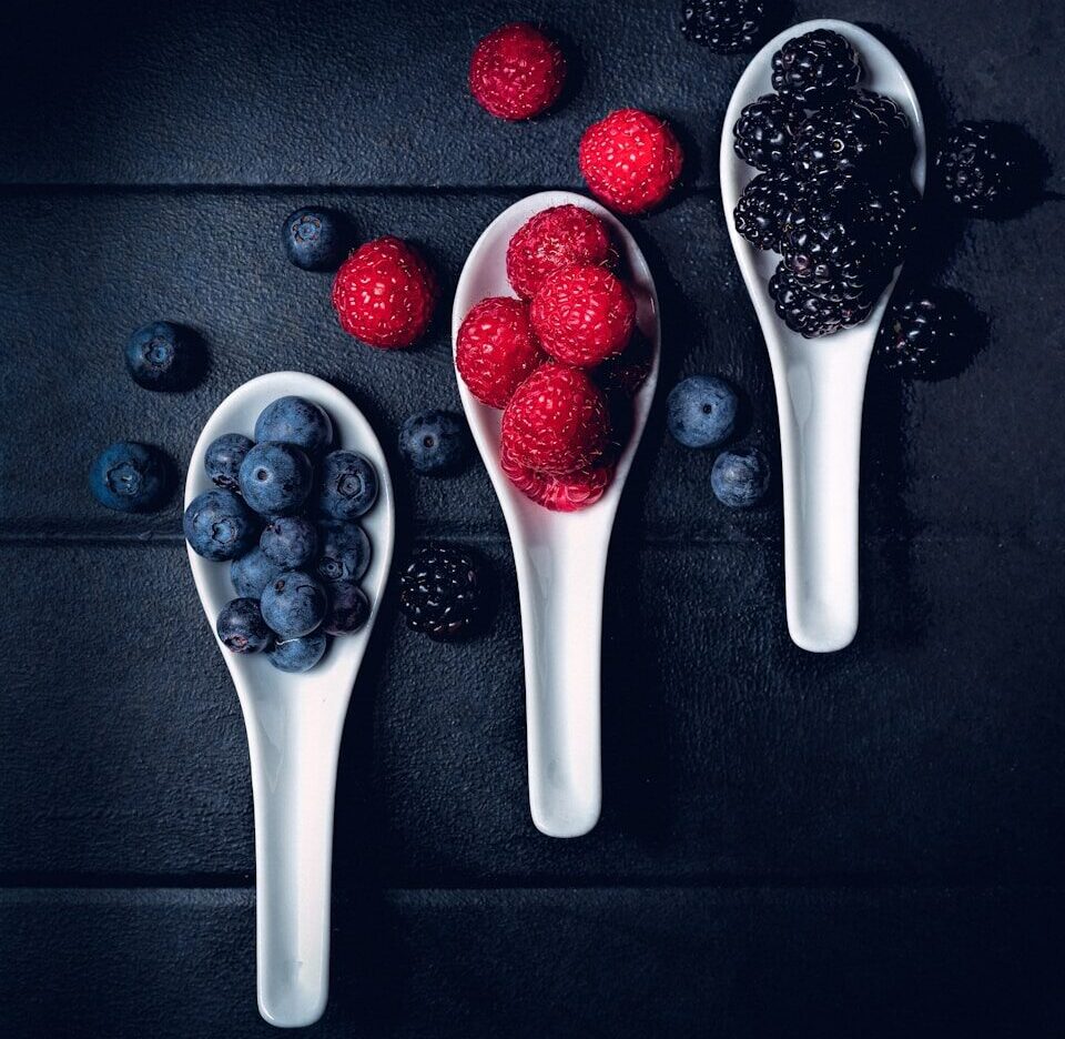 three ladles of berries on gray surface